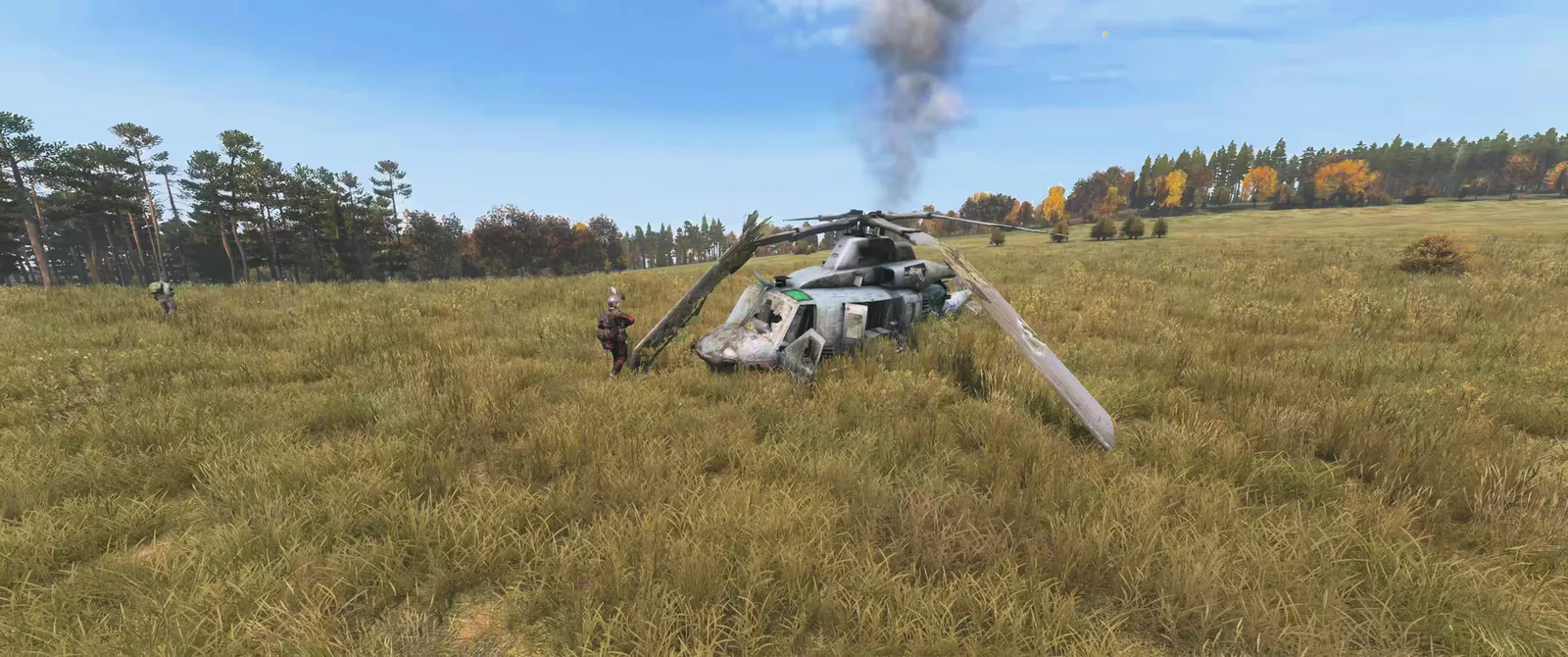 A downed military helicopter smoking in a field, with a survivor heading in to loot it