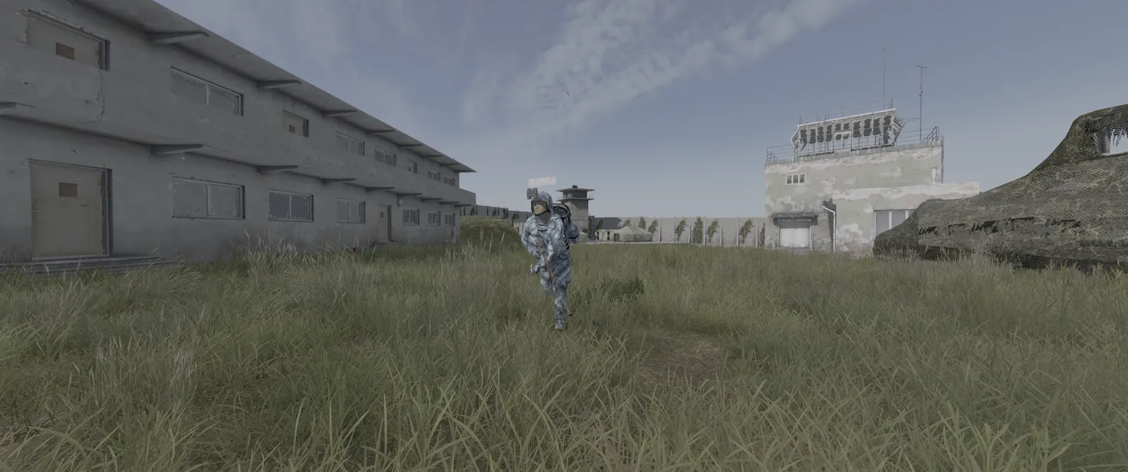 An Expansion AI soldier in winter camo running past barracks and an air traffic tower inside Outcasts Stronghold